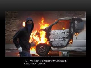 Fig. 1. Photograph of a masked youth walking past a burning vehicle from CNN .